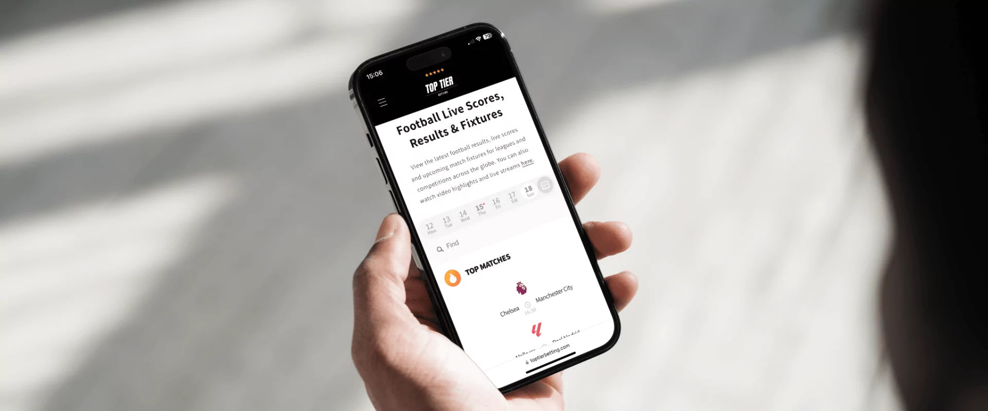 Man holding a smart phone looking at the latest football live scores, results & fixtures