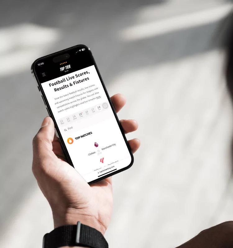 Man holding a smart phone looking at the latest football live scores, results & fixtures